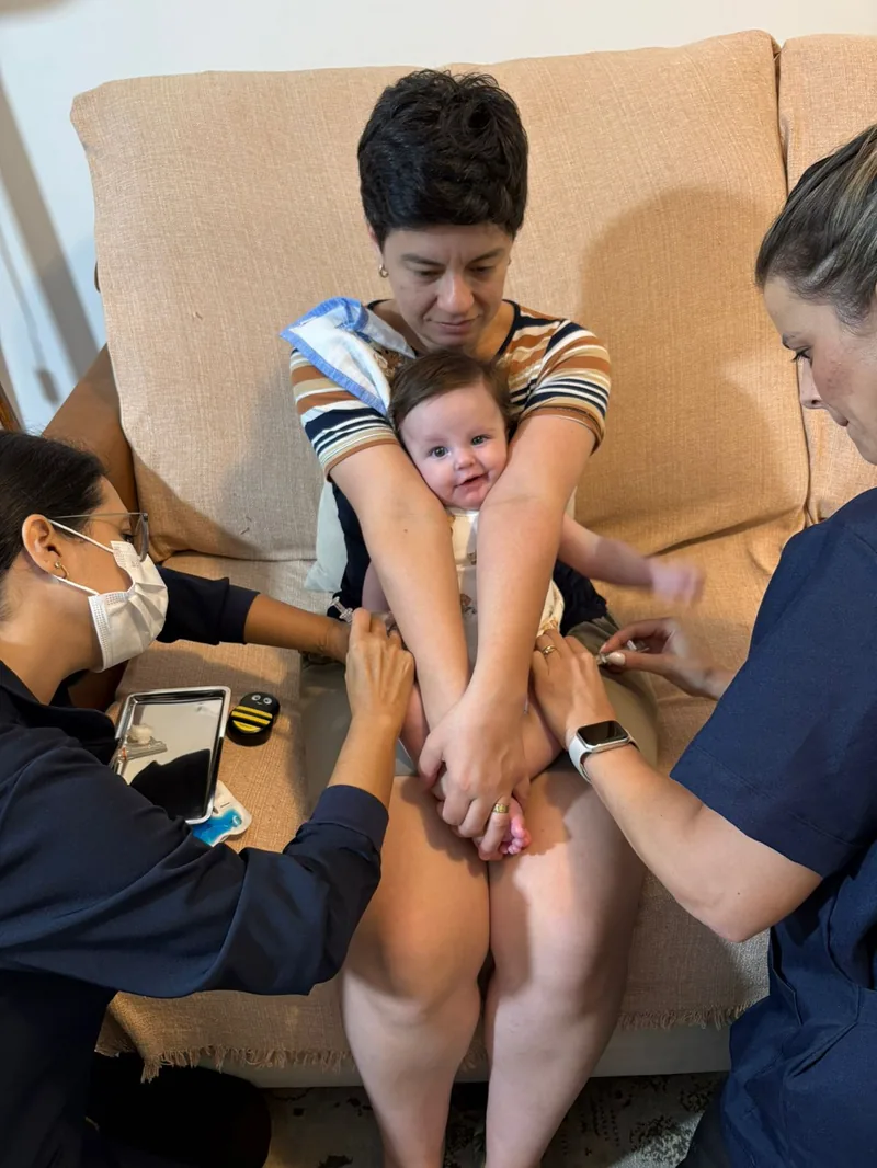 Técnica segurando o bebê com jeito durante a vacina em Porto Alegre